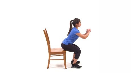 Person squatting to a chair performing an exercise.